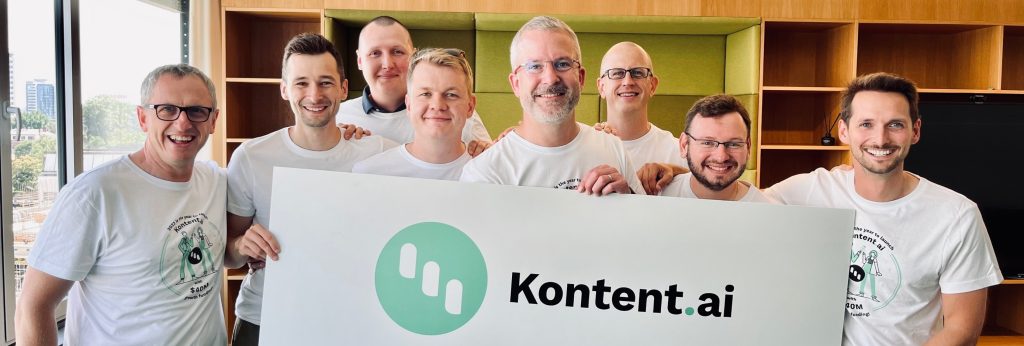 The Kontent.ai executive team holding large sign with their logo on